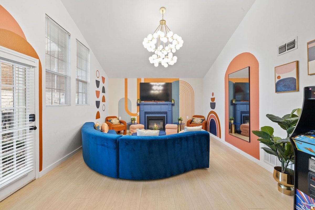 A modern living room with a curved blue sofa, a fireplace, and a television.