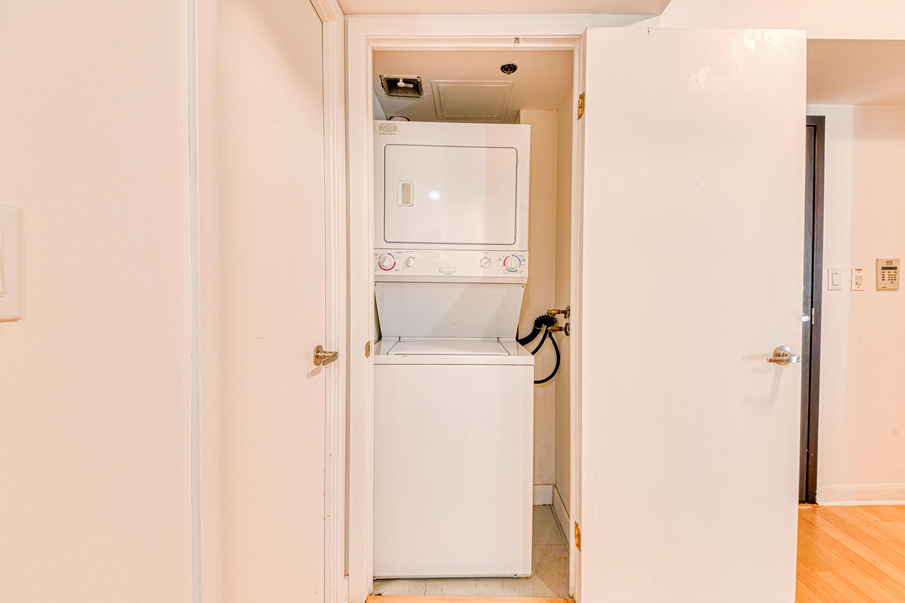 A laundry room with a washer and dryer, a door leading to another room, and a visible electrical outlet on the wall.