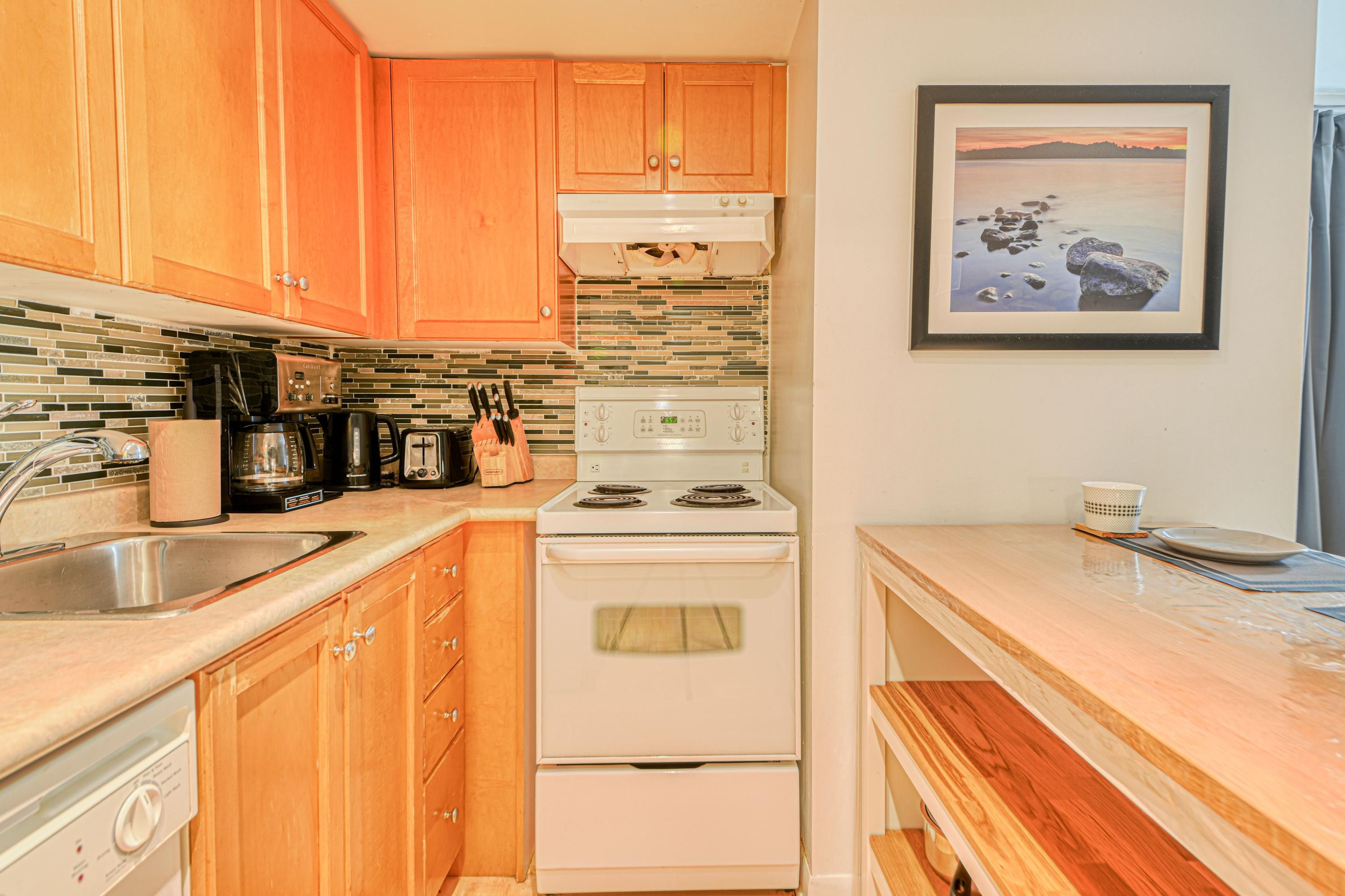 A kitchen with wooden cabinets, a white stove, and a tiled backsplash.