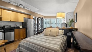 Um quarto moderno com uma cama grande, uma escrivaninha e uma cozinha compacta.