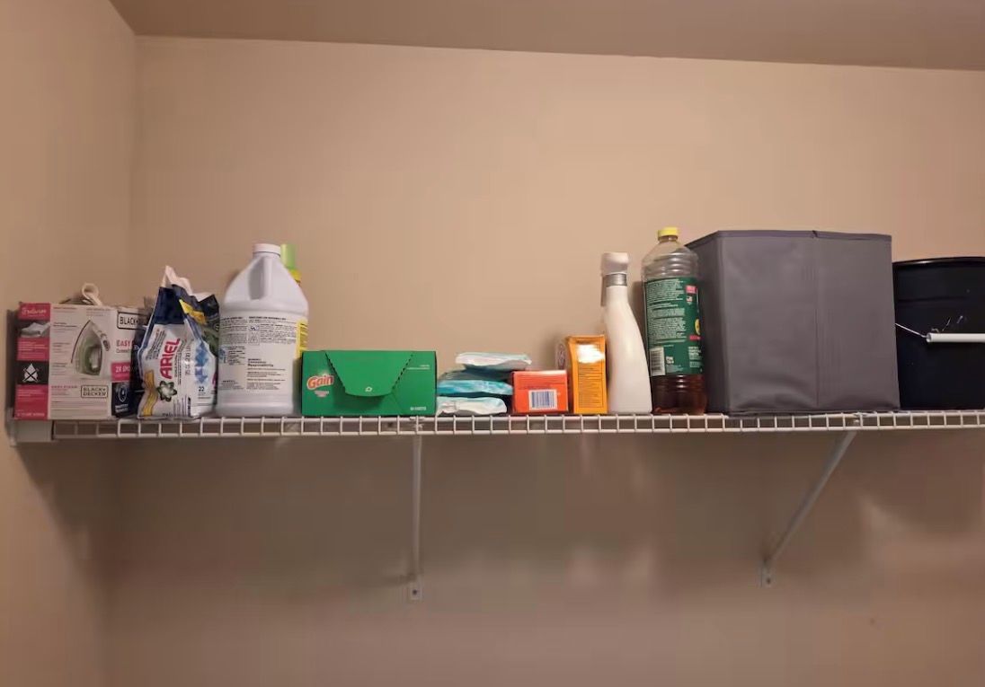 Estante con varios artículos del hogar, incluyendo productos de limpieza y una jarra de agua.