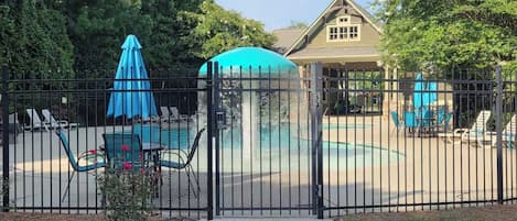 Une cour arrière clôturée avec une piscine, des chaises longues et un belvédère.