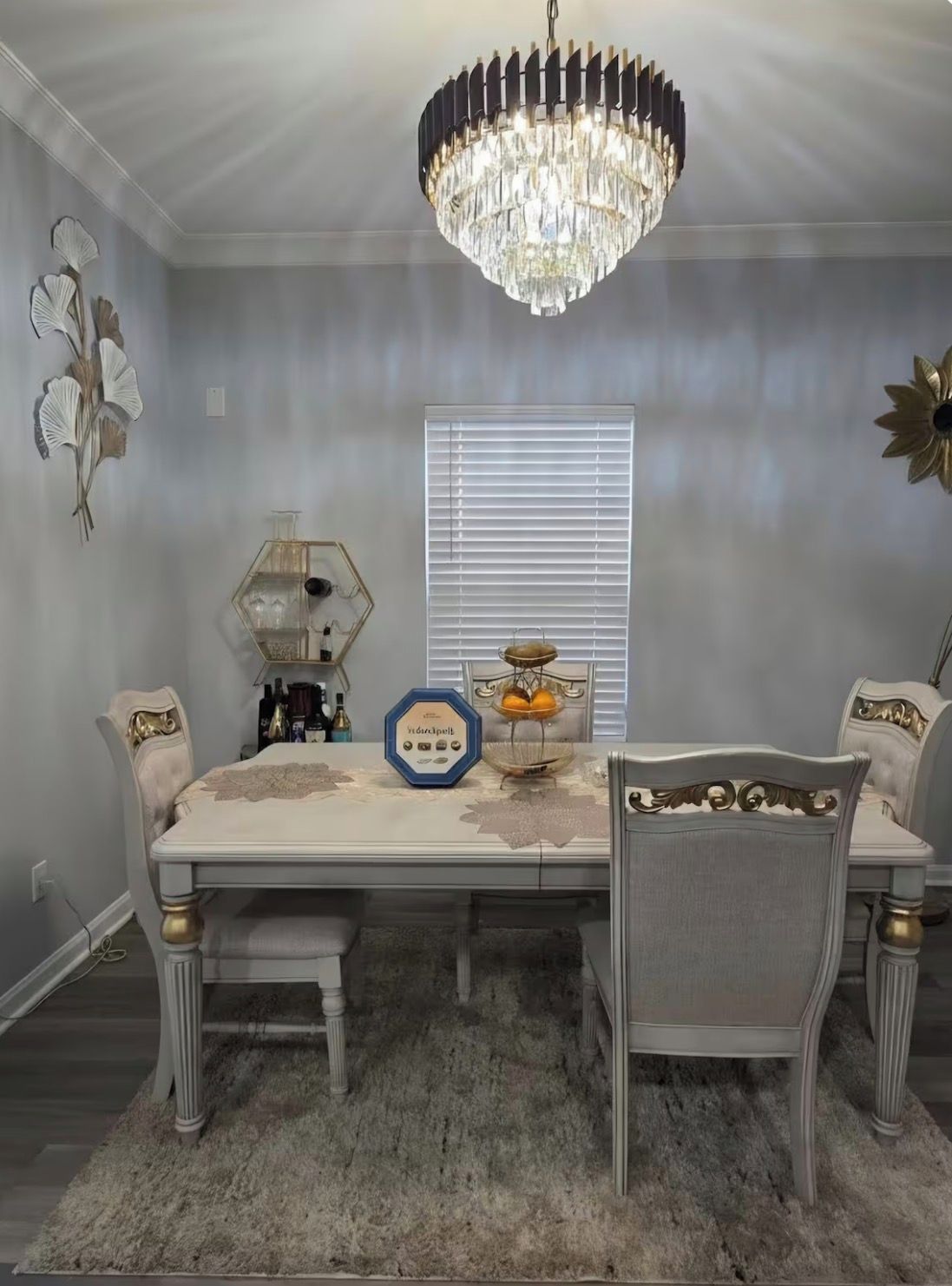A dining room with a chandelier, a round table, and chairs.