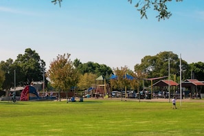 Un parque con juegos infantiles, zonas verdes y árboles.