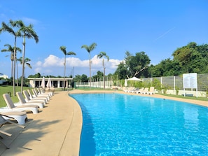 A swimming pool with lounge chairs, palm trees, and a fenced area. - Spacious 3-bedroom Ocean View apartment Flamingos Nuevo Vallarta (Nuevo Vallarta)