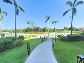 A pathway leading to a pool area with palm trees and a clear sky. - Spacious 3-bedroom Ocean View apartment Flamingos Nuevo Vallarta (Nuevo Vallarta)