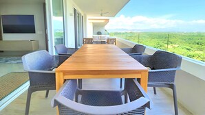A long wooden table with chairs on a balcony with a view of a green landscape. - Spacious 3-bedroom Ocean View apartment Flamingos Nuevo Vallarta (Nuevo Vallarta)