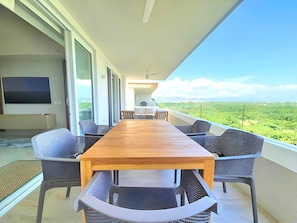 A long wooden table with chairs on a balcony with a view of a green landscape. - Spacious 3-bedroom Ocean View apartment Flamingos Nuevo Vallarta (Nuevo Vallarta)