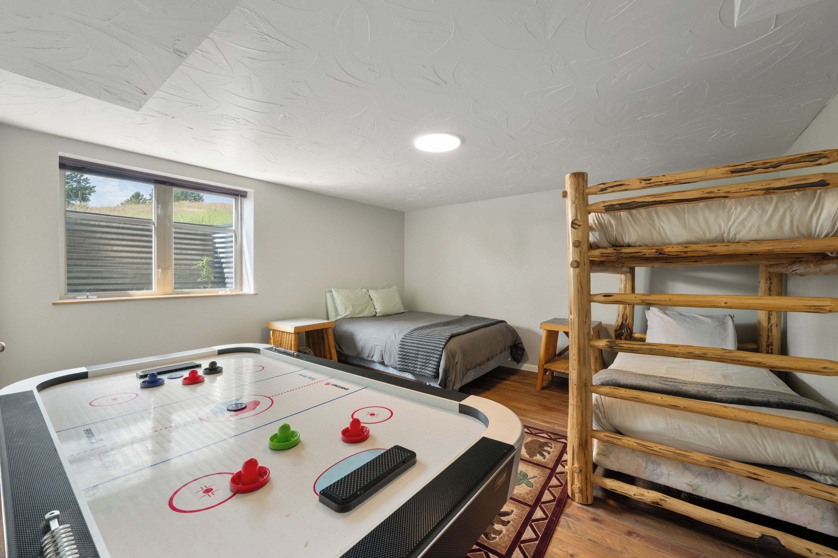 Huoneessa on shuffleboard-pöytä, kerrossängyt, ikkunasta avautuva näkymä ja kuvioitu katto.