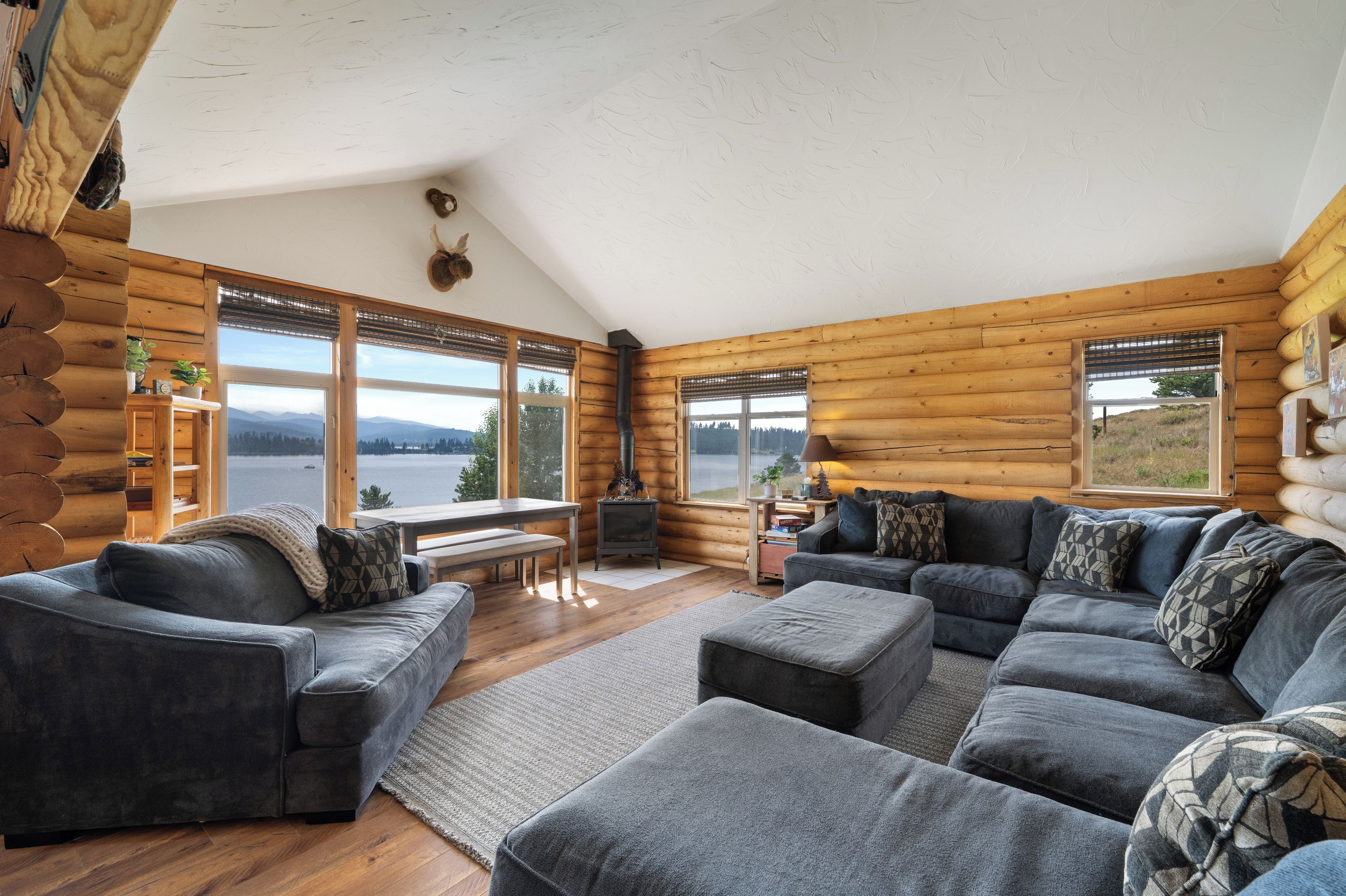 A log cabin interior with a sofa set, a table, and a fireplace.