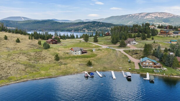 A lakeside property with multiple cabins, a dock with boats, and a mountainous backdrop. - Log Cabin Retreat | Private Dock & Mountain Views (Anaconda)