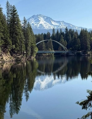 Un puente sobre un lago tranquilo con una montaña al fondo.