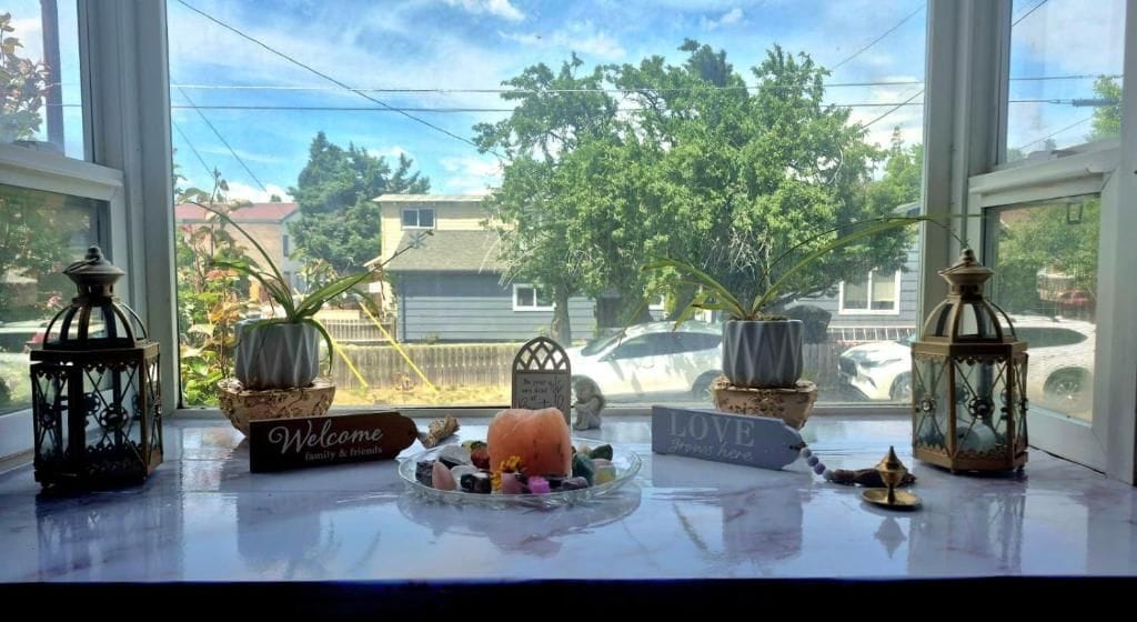 A window view with a welcome sign, a small table with decorative items, and two lanterns.