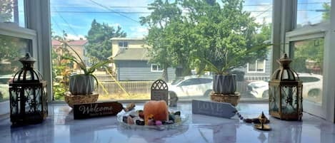 A window view with a welcome sign, a small table with decorative items, and two lanterns.