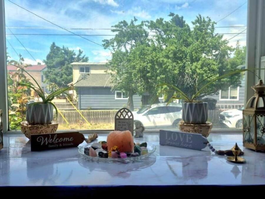 Vista por la ventana con un letrero de bienvenida, una mesita con adornos y dos faroles.