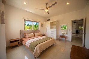 A bedroom with a bed, a wardrobe, a desk, and a ceiling fan.