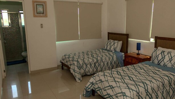 A hotel room with two beds, a nightstand, a framed picture on the wall, and a bathroom visible through an open door. - Hummingbird Palace at The Beach Club Condos (Quintana Roo)