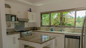 A kitchen with a stove, microwave, and dishwasher. - Hummingbird Palace at The Beach Club Condos (Quintana Roo)