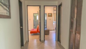 A hallway with a tiled floor, a red chair, and a wooden door on the right. - Hummingbird Palace at The Beach Club Condos (Quintana Roo)