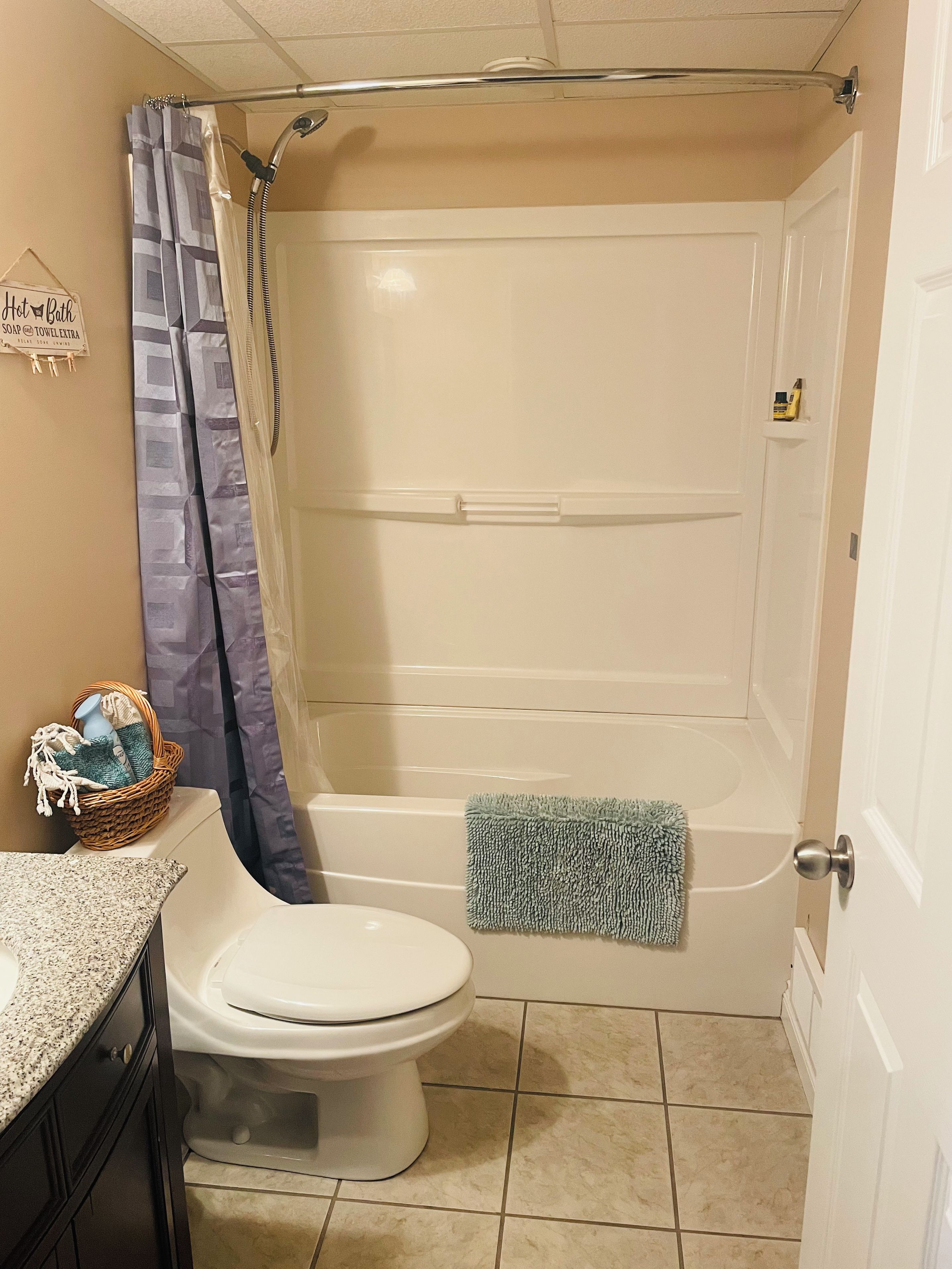 A bathroom with a toilet, a bathtub, a shower curtain, and a towel rack.