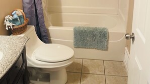 Un baño con inodoro, bañera, cortina de ducha y toallero.