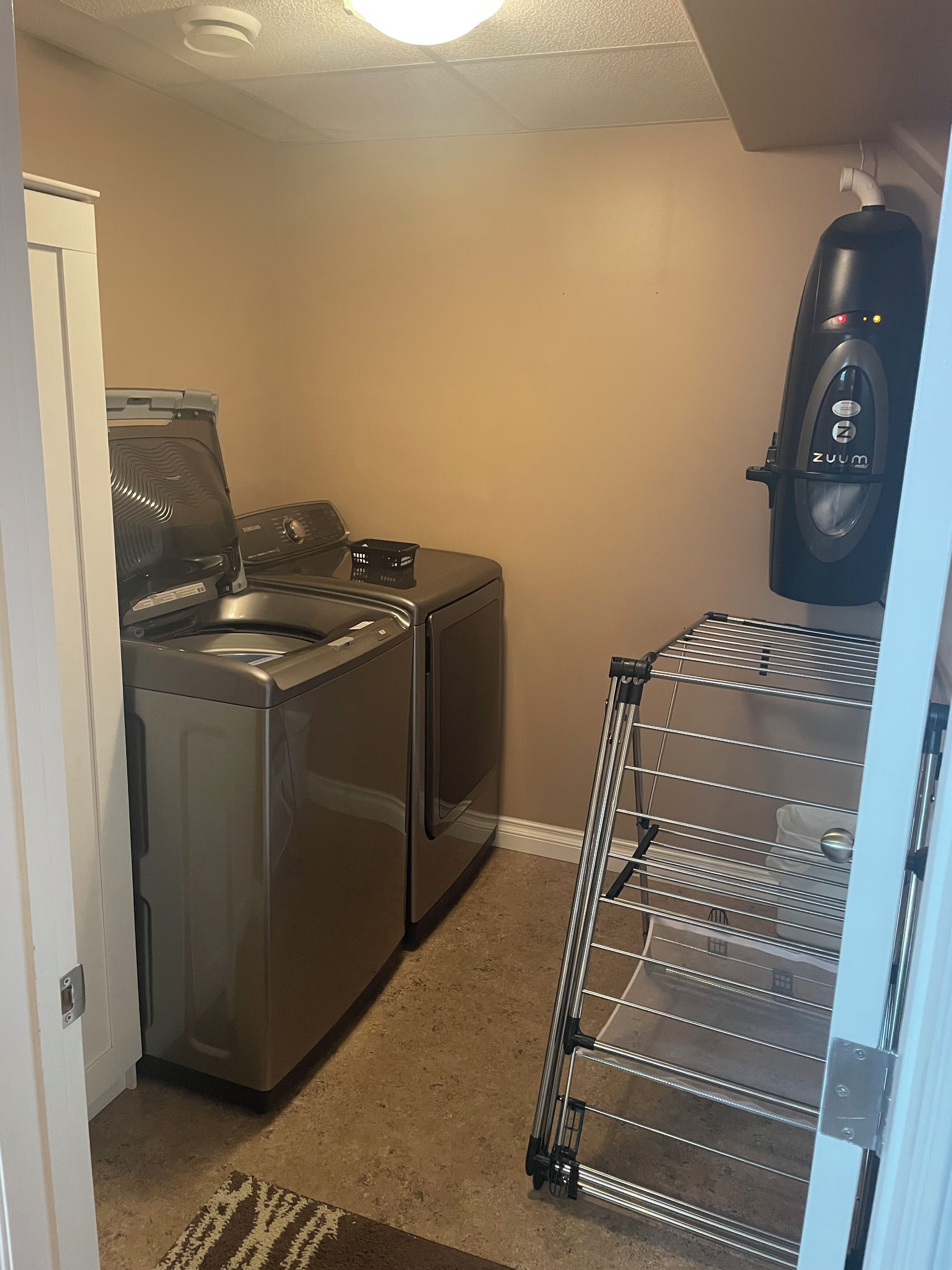 A laundry area with a washing machine, dryer, and a drying rack.