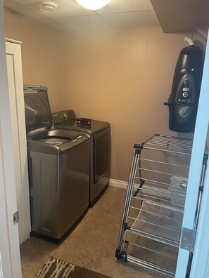 A laundry area with a washing machine, dryer, and a drying rack.