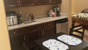 Una cocina con alacenas de madera oscura, una cafetera y una mesa con dos individuales.