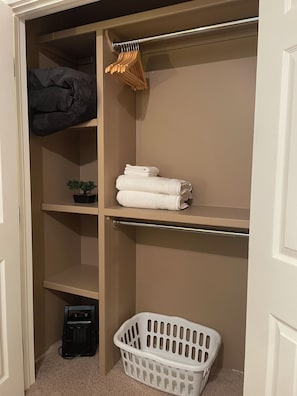 A closet with shelves, a hanging rack, and a laundry basket.