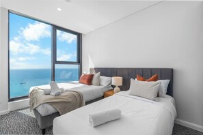 Une chambre d’hôtel avec deux lits, une grande fenêtre donnant sur la mer et un design moderne.