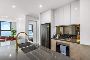 A modern kitchen with a stainless steel refrigerator, a built-in oven, and a countertop with a sink. - Beachfront Broadwater & Ocean Views 2BR w/ Parking (Surfers Paradise)