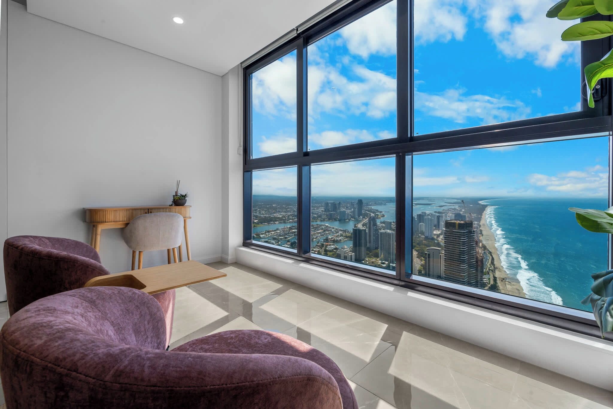 Ein modernes Zimmer mit einem großen Fenster und Blick auf eine Küstenstadt.