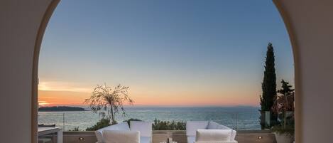 An outdoor seating area with a view of the sea during sunset.