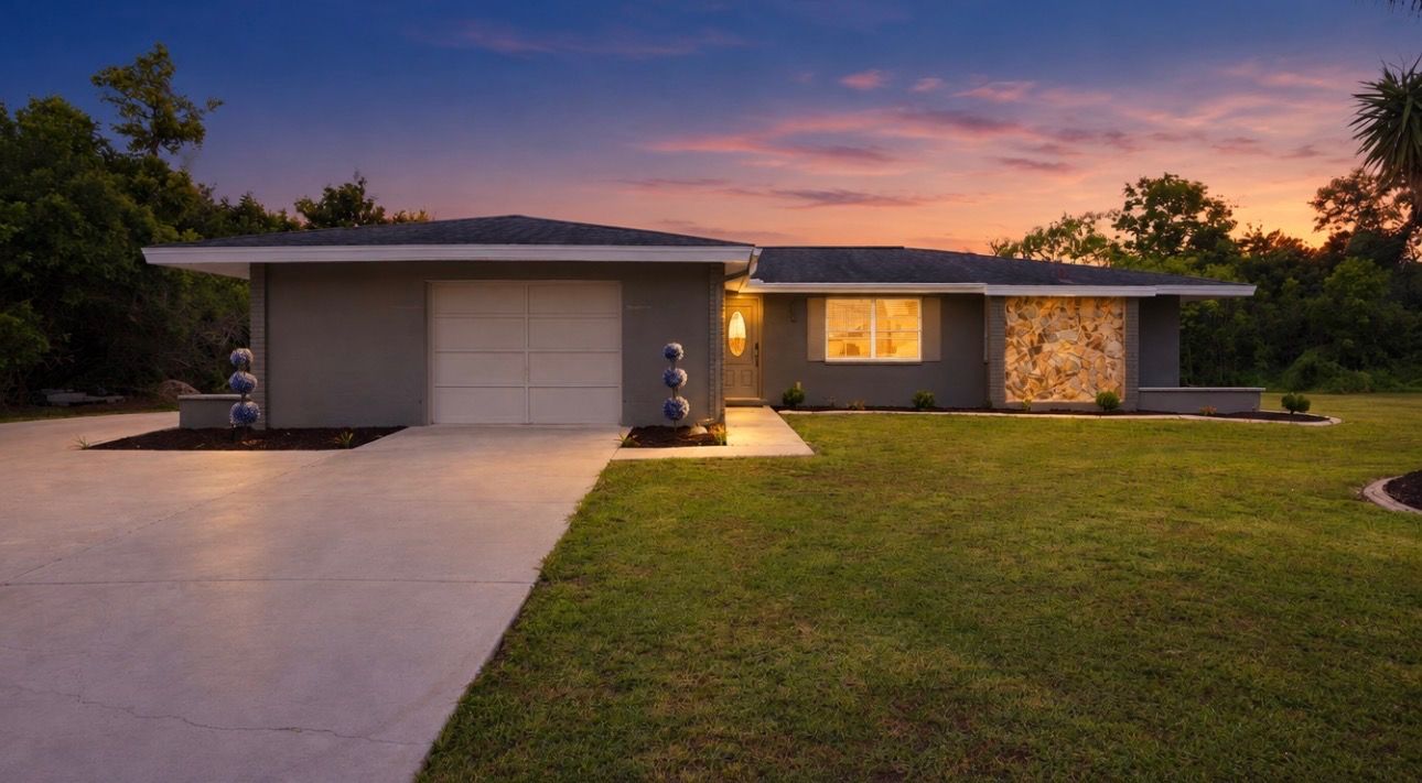 A modern two-story house with a garage, a well-maintained lawn, and a stone facade on one side.