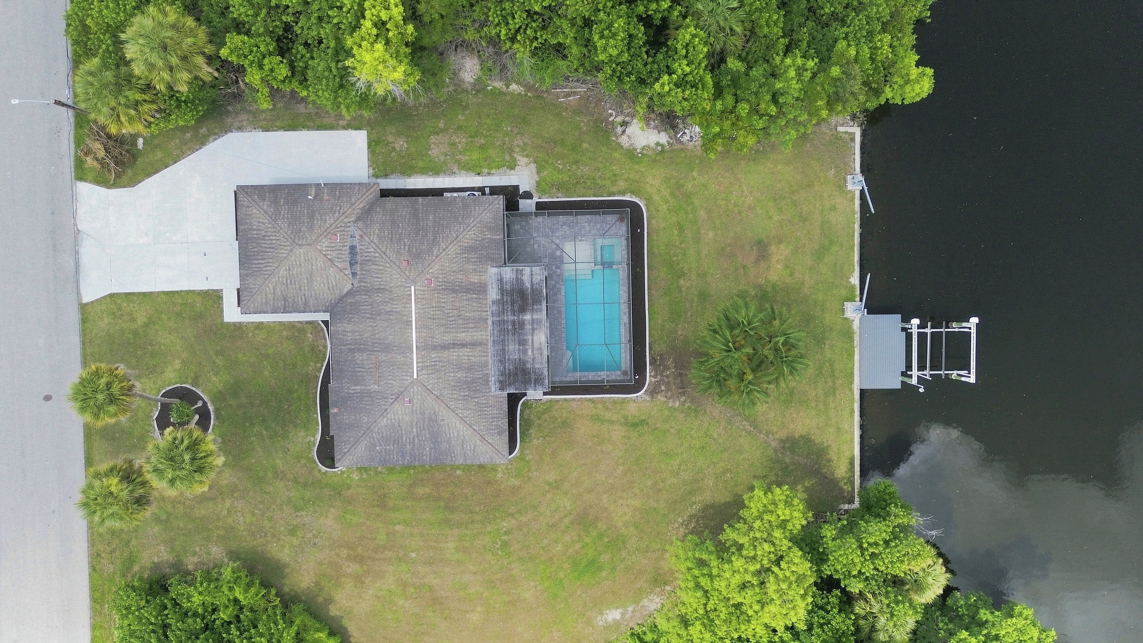 A residential property with a swimming pool, a covered patio, and a dock extending into a body of water.