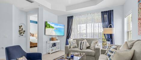 A modern living room with a sofa, armchair, and coffee table, a television, and a ceiling fan.