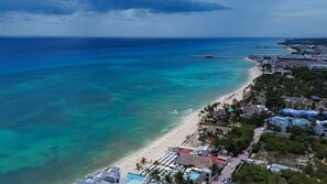 An aerial view of a coastal area with a beach, clear blue waters, and buildings along the shore. - Ocean View / Fitness Center / Private Beach / Huge Pool (Playa Del Carmen)