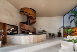 A modern lobby with a spiral staircase, a reception desk, seating area, and potted plants. - Ocean View / Fitness Center / Private Beach / Huge Pool (Playa Del Carmen)
