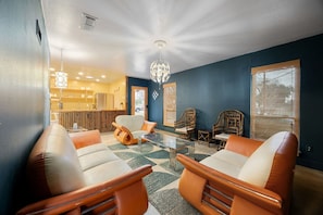 A living room with leather sofas, a glass coffee table, and a chandelier. - Austin Cowboy Pool w/ Sauna - Pet Friendly - Fire Pit (Austin)
