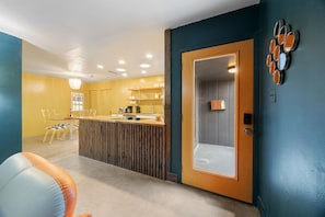 A room with a wooden reception desk, a seating area with chairs, and a door with a mirror. - Austin Cowboy Pool w/ Sauna - Pet Friendly - Fire Pit (Austin)