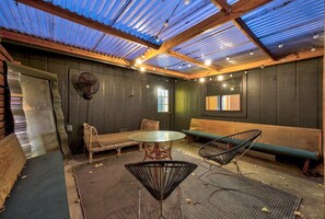 A room with a high ceiling, wooden beams, a green bench, a round table, and two chairs. - Austin Cowboy Pool w/ Sauna - Pet Friendly - Fire Pit (Austin)