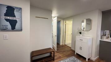 A hallway with a wooden bench, a white radiator, a mirror, and a rug.