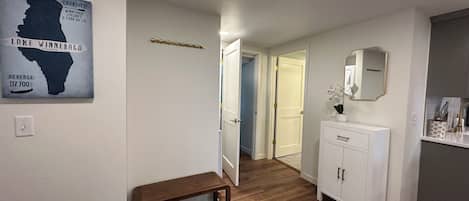 Un pasillo con un banco de madera, un radiador blanco, un espejo y una alfombra.