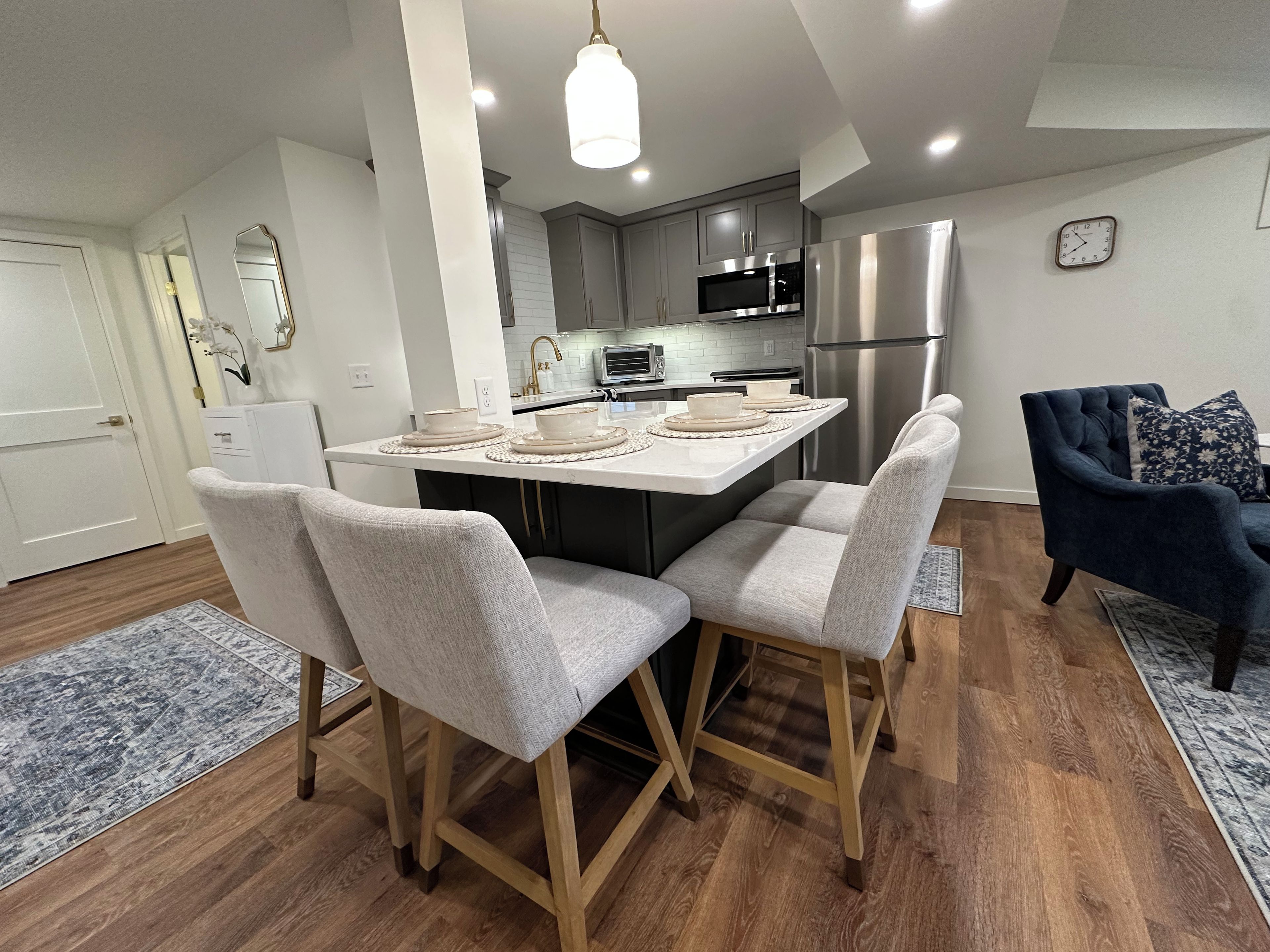 A modern kitchen with a central island, stainless steel appliances, and a dining area with two chairs.