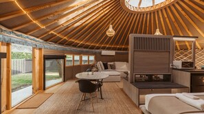 Habitación tipo yurta con una mesa redonda, sofá y una zona de kitchenette.