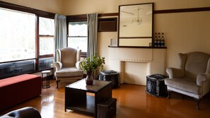 A room with a large window, a chair, a small table with a vase, and a mirror on the wall. - Warburton Stays | Grand View (Warburton)