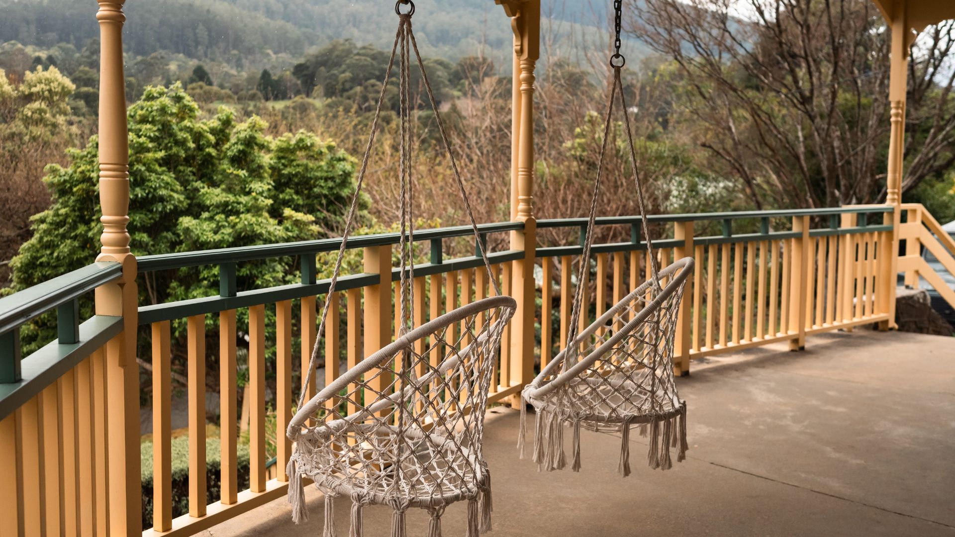 Una silla colgante sujeta a una estructura de madera, con vista a un paisaje boscoso.