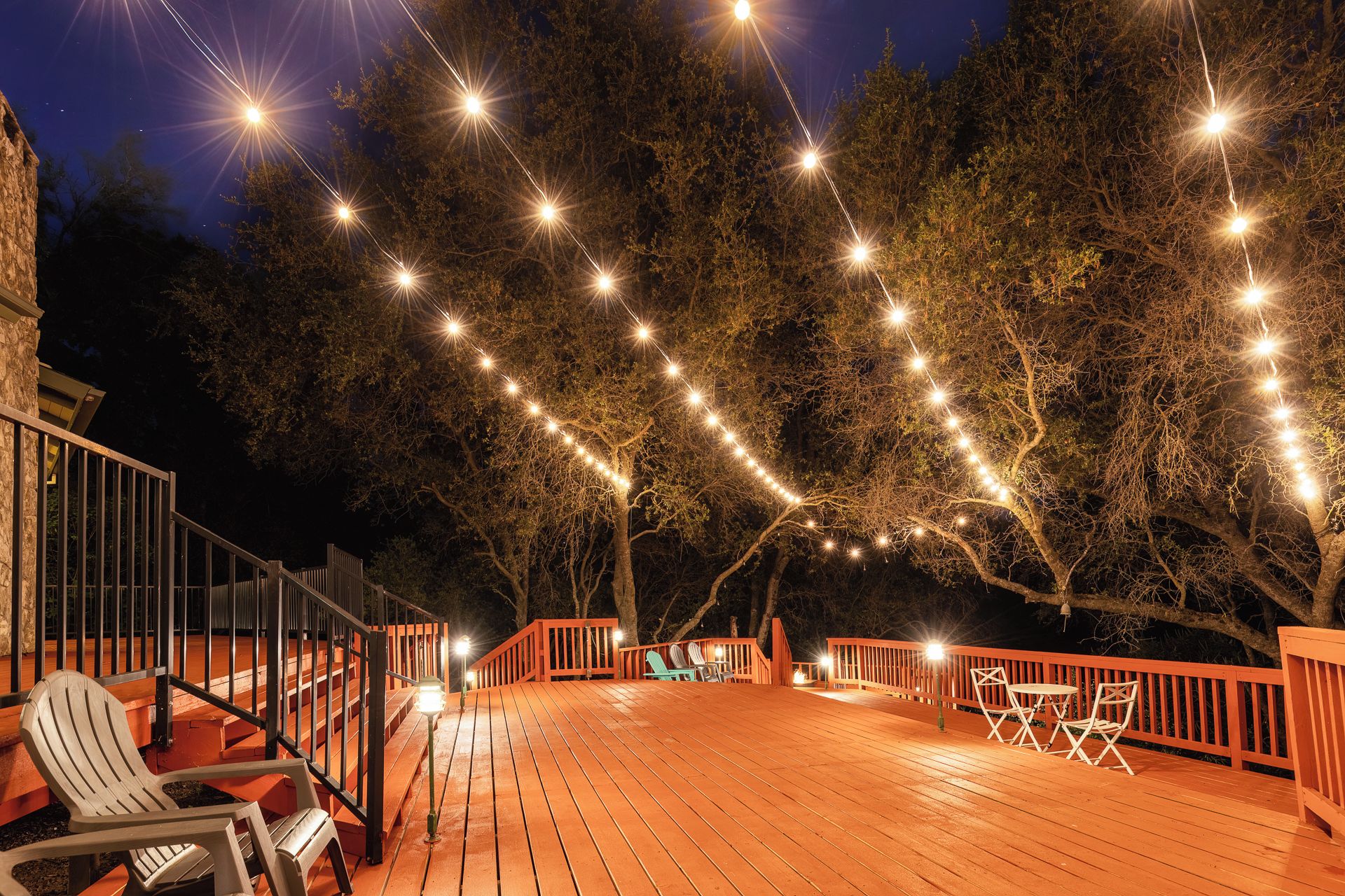 A wooden deck with outdoor seating and string lights.