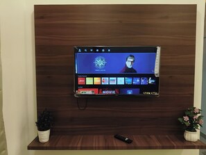 Un televisor de pantalla plana montado en una pared de madera, con un control remoto en el suelo.