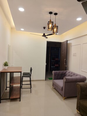 A modern living room with a dining area, a ceiling fan, and a purple sofa. - Peaceful 1-bedroom apartment with AC in vibrant Thane (Thane)